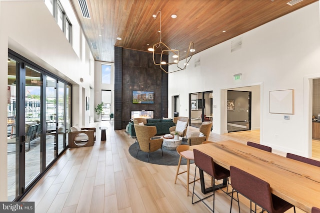 dining space with wood ceiling, light hardwood / wood-style flooring, and a high ceiling