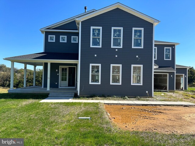 rear view of property featuring a lawn and covered porch