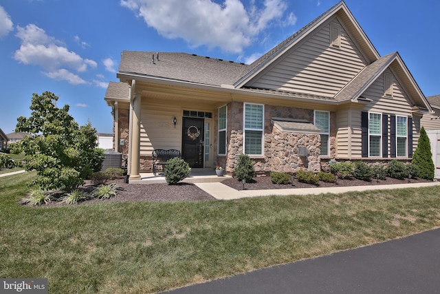 view of front of house featuring cooling unit, a front lawn, and covered porch