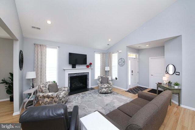 living room with lofted ceiling, a fireplace, and light hardwood / wood-style floors