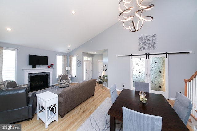 living room featuring plenty of natural light, a barn door, vaulted ceiling, and light hardwood / wood-style flooring