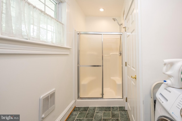 full bathroom with a stall shower, washer / clothes dryer, baseboards, and heating unit