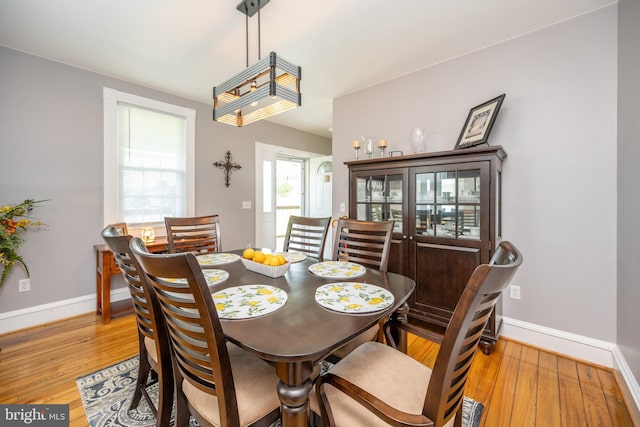 dining space with light wood-type flooring and baseboards