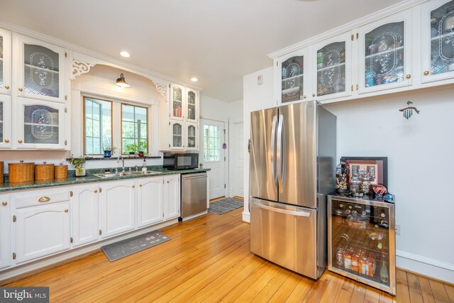 kitchen featuring wine cooler, light hardwood / wood-style flooring, stainless steel appliances, sink, and white cabinetry