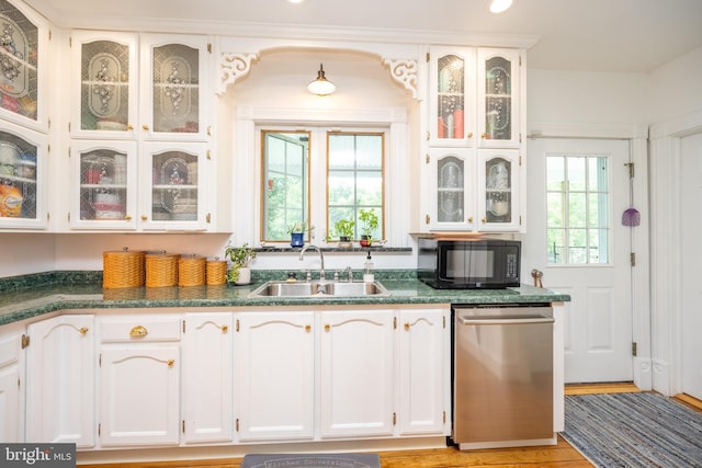 kitchen with glass insert cabinets, white cabinetry, a sink, black microwave, and dishwasher