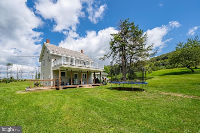 rear view of property with a lawn, a chimney, and a wooden deck