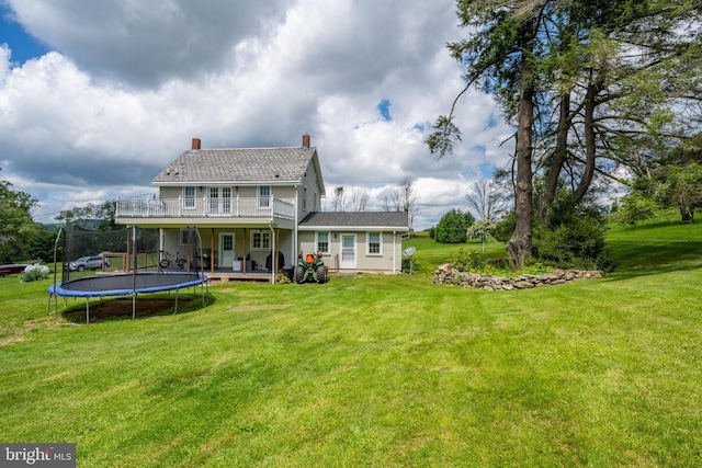 rear view of house with a chimney, a deck, and a lawn