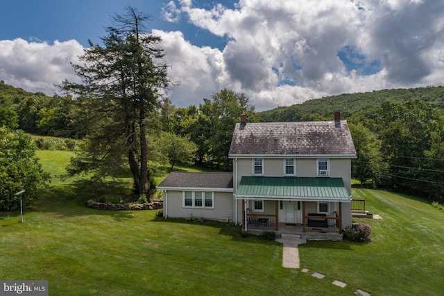 view of front of house with a porch, a wooded view, and a front yard