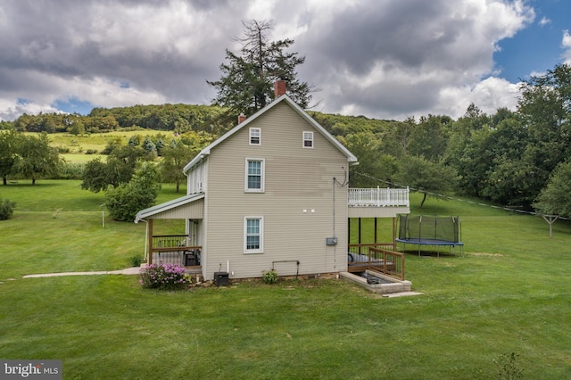 view of home's exterior featuring a forest view, a trampoline, central AC, and a yard