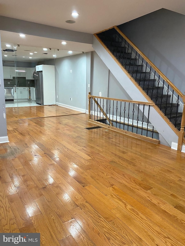 unfurnished living room featuring stairway, recessed lighting, light wood-style flooring, and baseboards