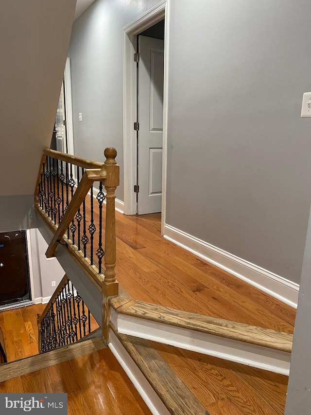 stairway with wood finished floors and baseboards