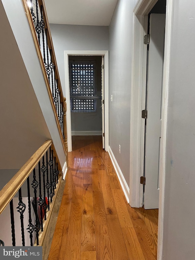 corridor with stairs, light wood-type flooring, and baseboards