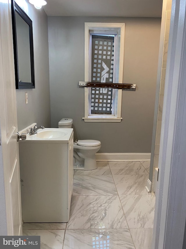 bathroom featuring marble finish floor, vanity, toilet, and baseboards