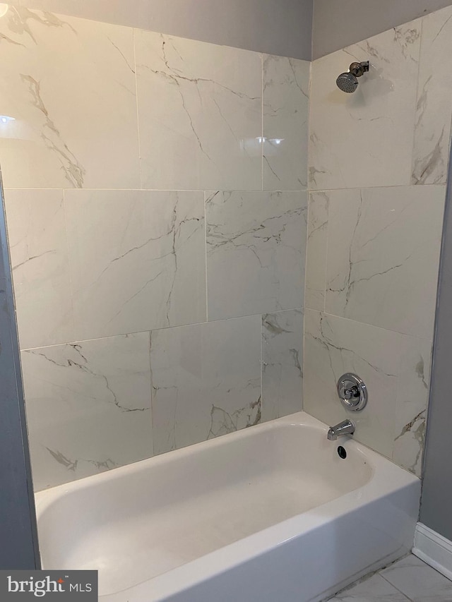 bathroom featuring marble finish floor and shower / washtub combination