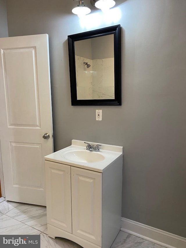 bathroom with marble finish floor, baseboards, a shower, and vanity