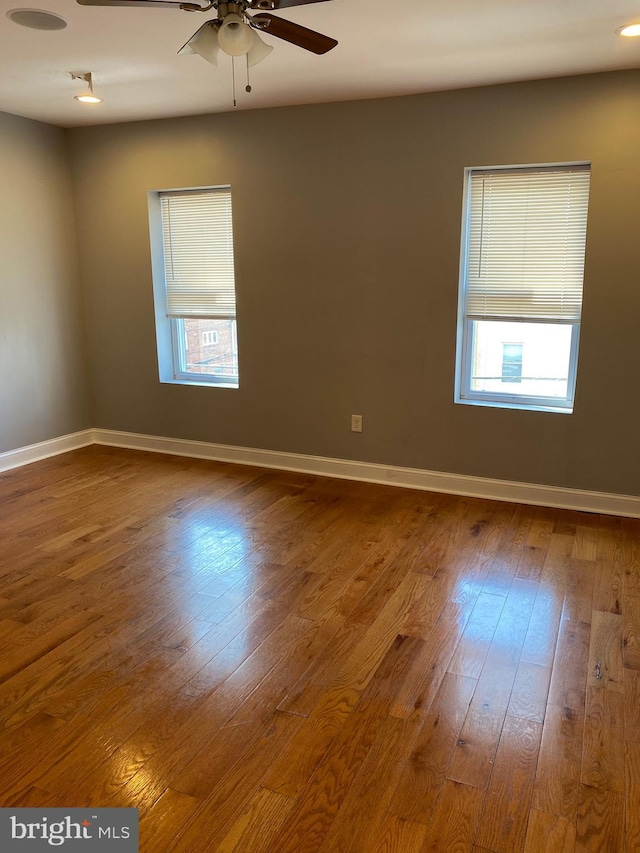 spare room featuring ceiling fan, baseboards, and wood finished floors