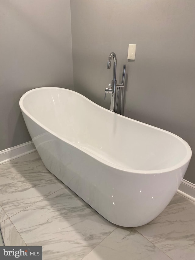 interior details featuring a freestanding bath and baseboards