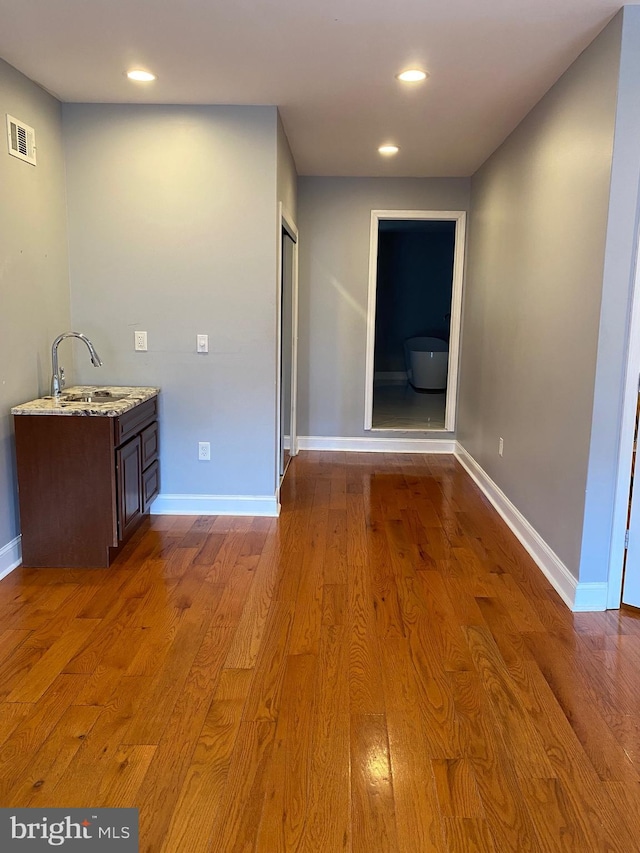 corridor with recessed lighting, a sink, visible vents, baseboards, and light wood-type flooring