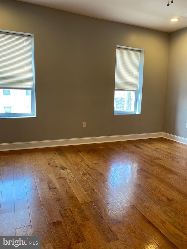 empty room with recessed lighting, baseboards, and wood finished floors