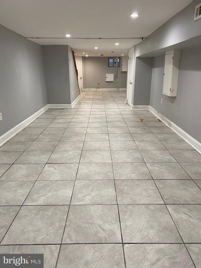 finished below grade area with light tile patterned floors, recessed lighting, visible vents, and baseboards