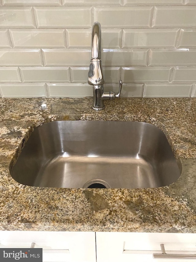 room details featuring dark stone countertops, a sink, and white cabinetry