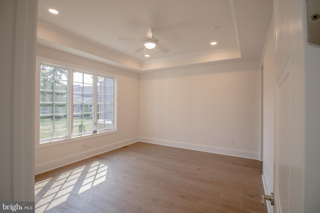 unfurnished room featuring ceiling fan, ornamental molding, light hardwood / wood-style flooring, and a raised ceiling