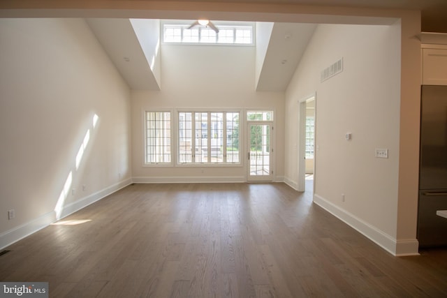 unfurnished living room with plenty of natural light, dark wood-type flooring, and high vaulted ceiling