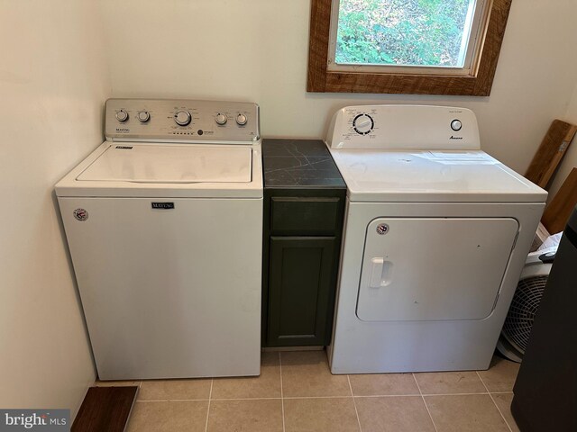 washroom with cabinets, light tile patterned floors, and washer and clothes dryer