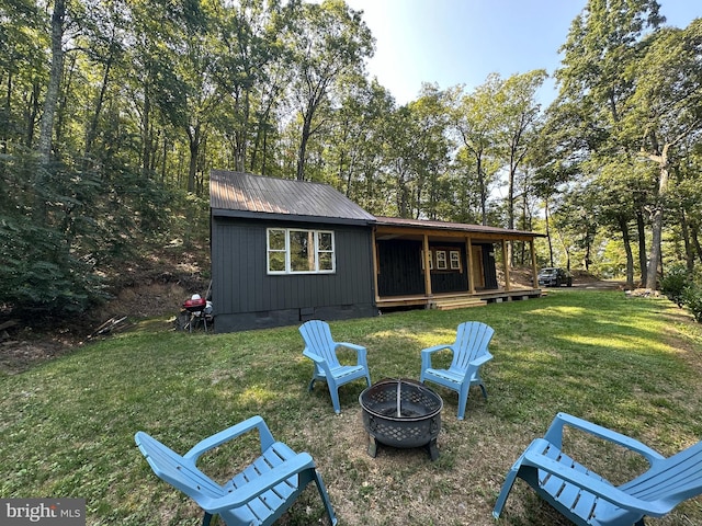 rear view of house with a yard and an outdoor fire pit