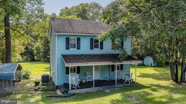 view of front of property featuring a patio area, a shed, a front yard, and central AC