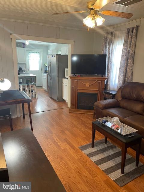 living room with hardwood / wood-style floors, ceiling fan, and crown molding