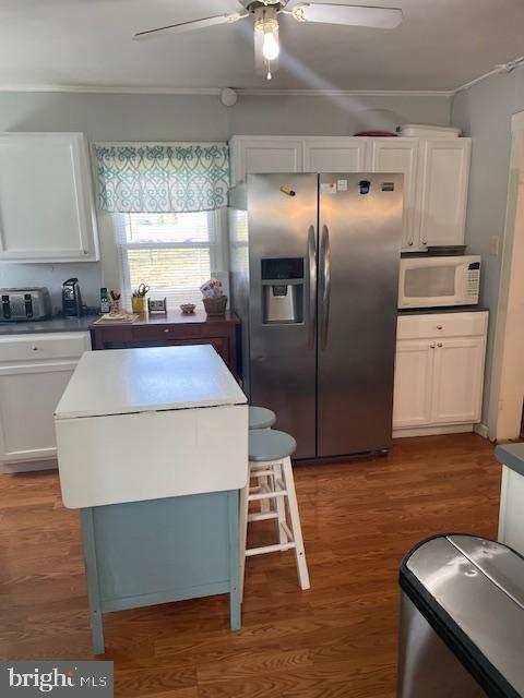 kitchen with white cabinetry, a center island, ceiling fan, dark hardwood / wood-style floors, and stainless steel fridge