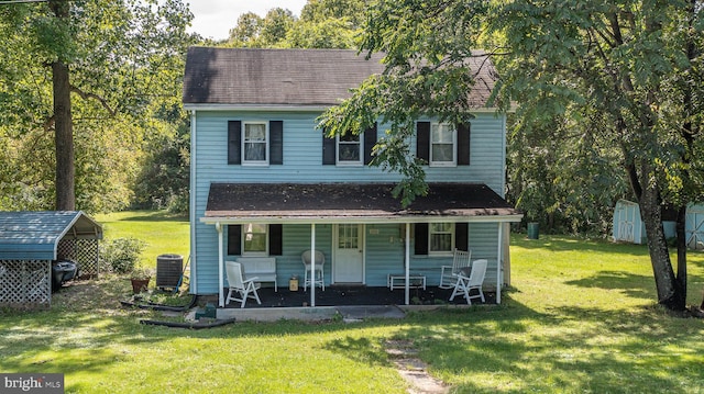 view of front of property with central AC, covered porch, a front yard, and a storage shed