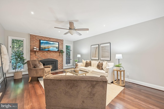 living room with a brick fireplace, ceiling fan, and dark hardwood / wood-style flooring