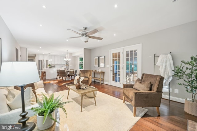 living room with wood-type flooring and ceiling fan with notable chandelier