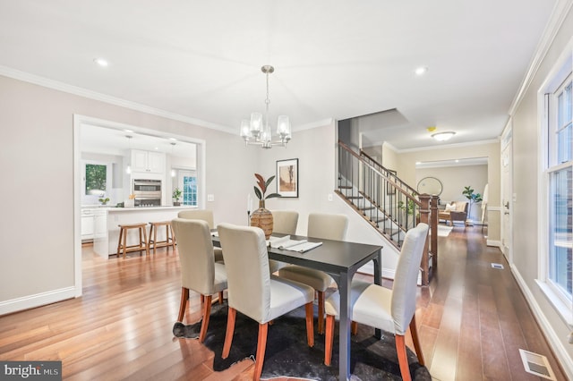 dining space featuring light hardwood / wood-style floors, ornamental molding, and a healthy amount of sunlight