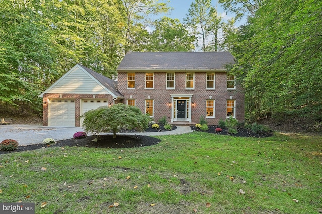 colonial inspired home featuring a garage and a front lawn