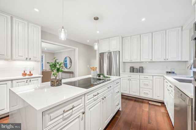 kitchen with a kitchen island, dark hardwood / wood-style floors, white cabinetry, appliances with stainless steel finishes, and decorative light fixtures