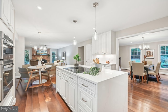 kitchen with a brick fireplace, black electric cooktop, dark hardwood / wood-style flooring, and white cabinetry