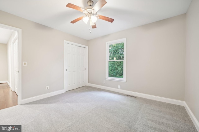 unfurnished bedroom with ceiling fan, light colored carpet, and a closet