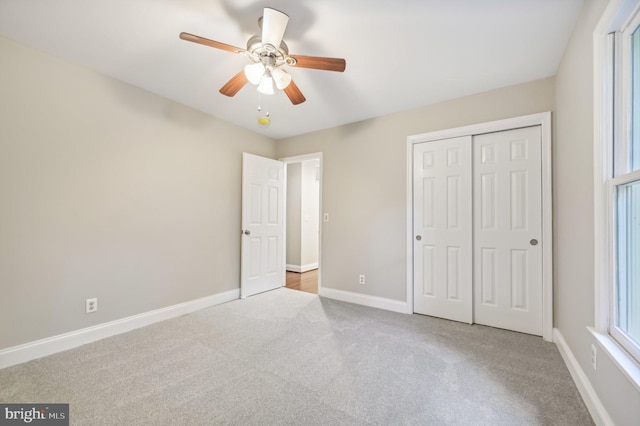 unfurnished bedroom with a closet, light colored carpet, and ceiling fan