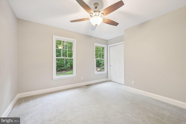 empty room with ceiling fan and light carpet