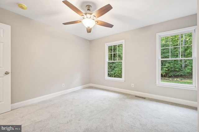 spare room with ceiling fan, light colored carpet, and plenty of natural light