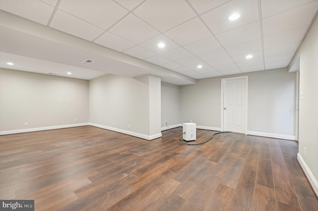 basement with a paneled ceiling and dark hardwood / wood-style flooring