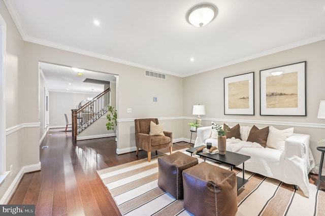 living room featuring ornamental molding, dark wood-type flooring, and an inviting chandelier