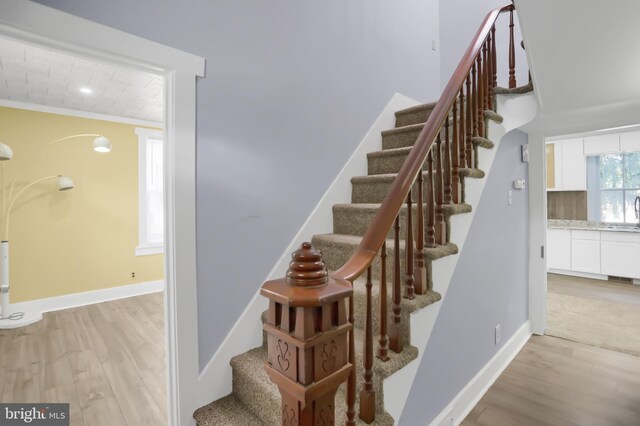 stairway featuring crown molding and wood-type flooring