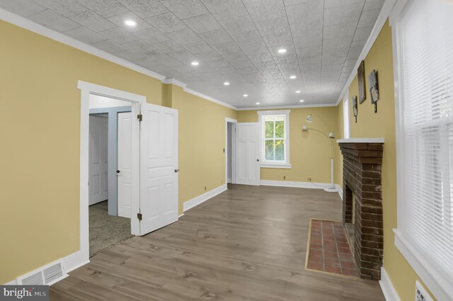 unfurnished living room with hardwood / wood-style floors, a brick fireplace, and ornamental molding