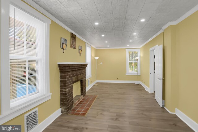 living room featuring wood-type flooring, a brick fireplace, and ornamental molding