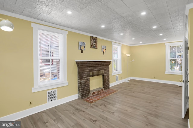 unfurnished living room featuring hardwood / wood-style flooring, a fireplace, and crown molding