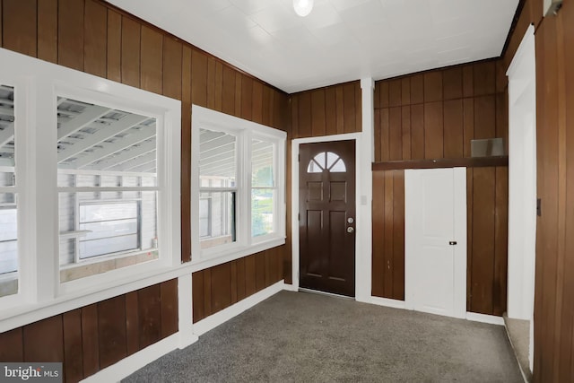 carpeted entrance foyer with wood walls